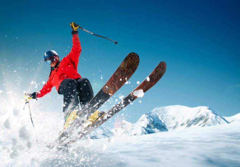 Skieur en pleine glisse dans la poudreuse, face à des sommets enneigés