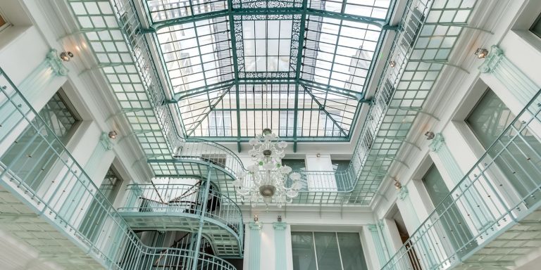Atrium sous verrière avec grand lustre et galeries métalliques, lieu de la convention EIT Manufacturing
