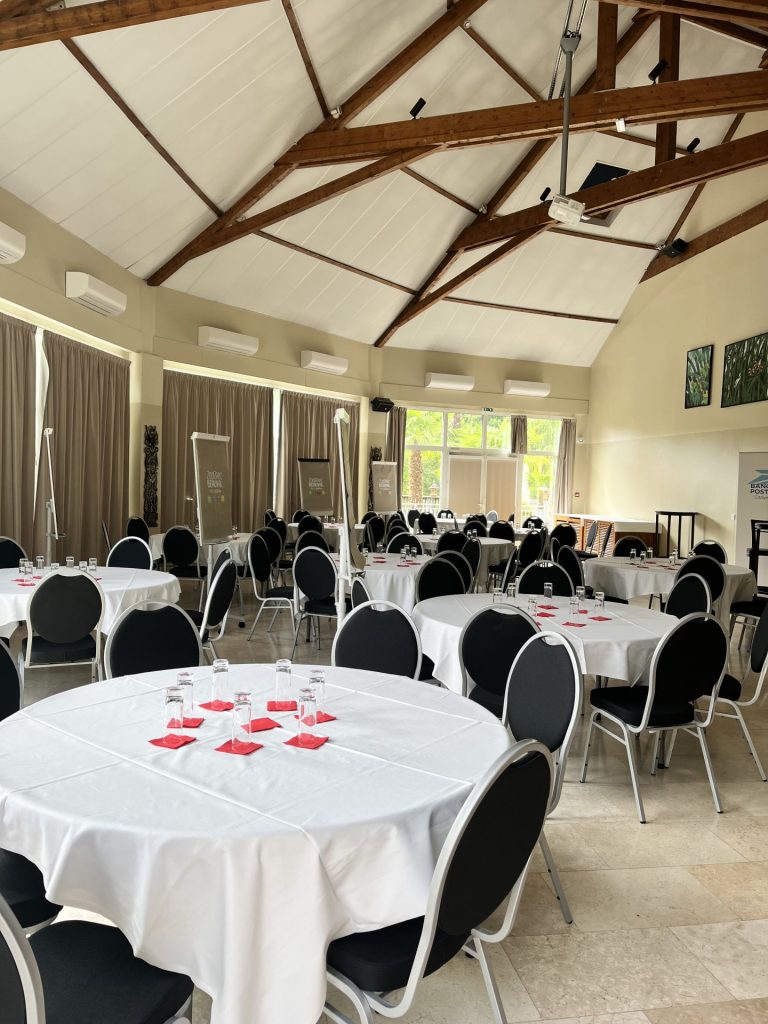 Salle de restaurant aux tables rondes nappées de blanc, dressée pour le séminaire d’un groupe bancaire organisé par Weevup au Zoo de Beauval