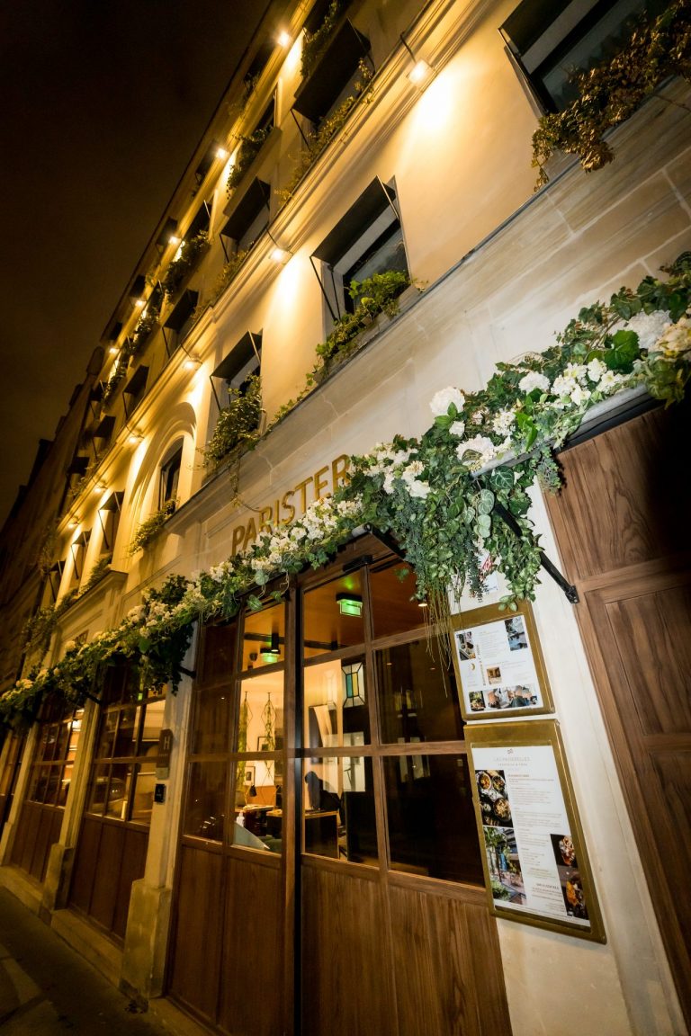 Façade illuminée d’un bar parisien ornée d’une guirlande fleurie, lieu de l’afterwork DeepLife