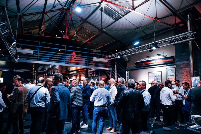 Invités de la soirée Hanwha Techwin réunis sous une charpente métallique éclairée, après leur journée de salon