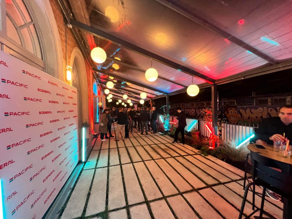Invités sur la terrasse éclairée, le long d’un mur aux logos de la marque, pendant la soirée de lancement Groupe Atlantic organisée par Weevup