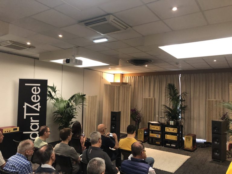 Démonstration d’enceintes haute fidélité devant un public assis, dans un showroom du salon Publison