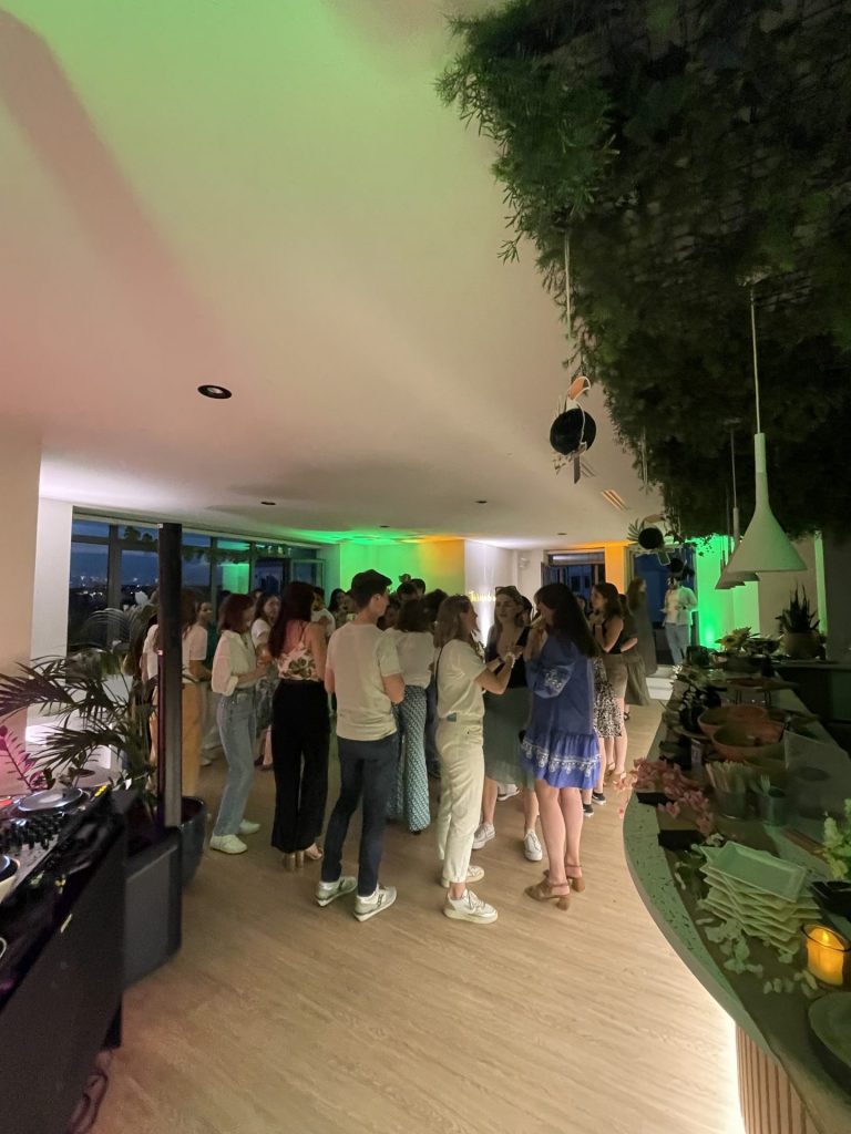 Collaborateurs de Havea Group réunis près du bar, sous un plafond végétal et des lumières vertes, pendant la summer party organisée par Weevup dans leurs locaux parisiens