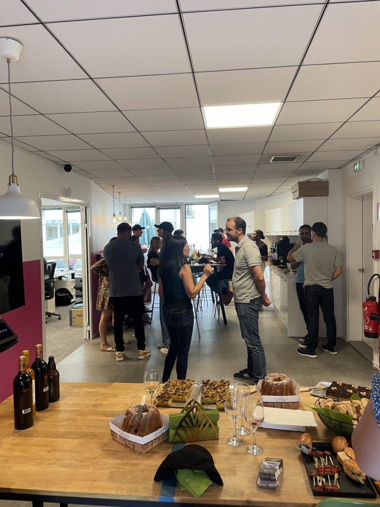 Buffet de l’afterwork Ouicar au premier plan, avec les invités qui échangent debout au fond de la salle, soirée organisée par Weevup