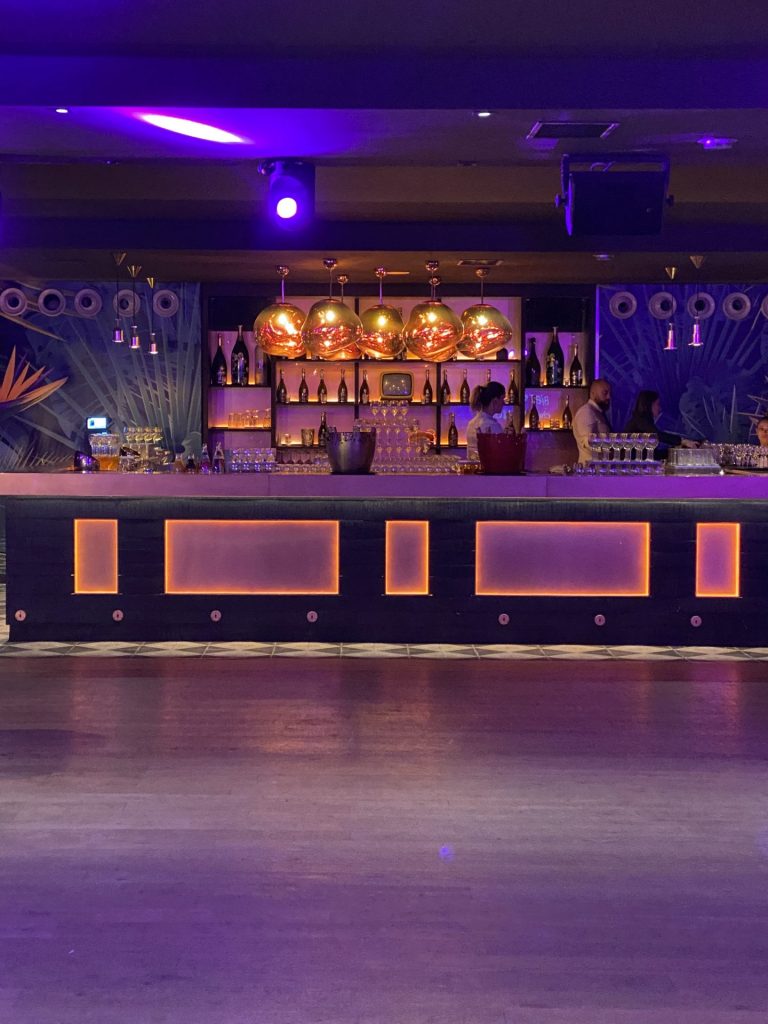 Bar décoré au comptoir lumineux, sous des suspensions cuivrées, avant l’arrivée des invités de la soirée cocktail Scalian organisée par Weevup