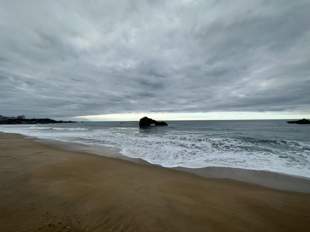 Plage et océan sous un ciel couvert, avec un rocher au large, pendant le séminaire résidentiel Husqvarna à Biarritz