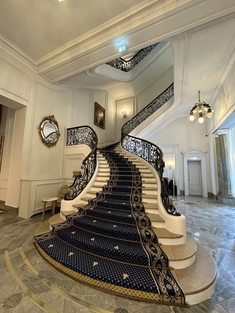 Escalier d’honneur à rampe en fer forgé et tapis bleu de l’hôtel du séminaire résidentiel Husqvarna, à Biarritz