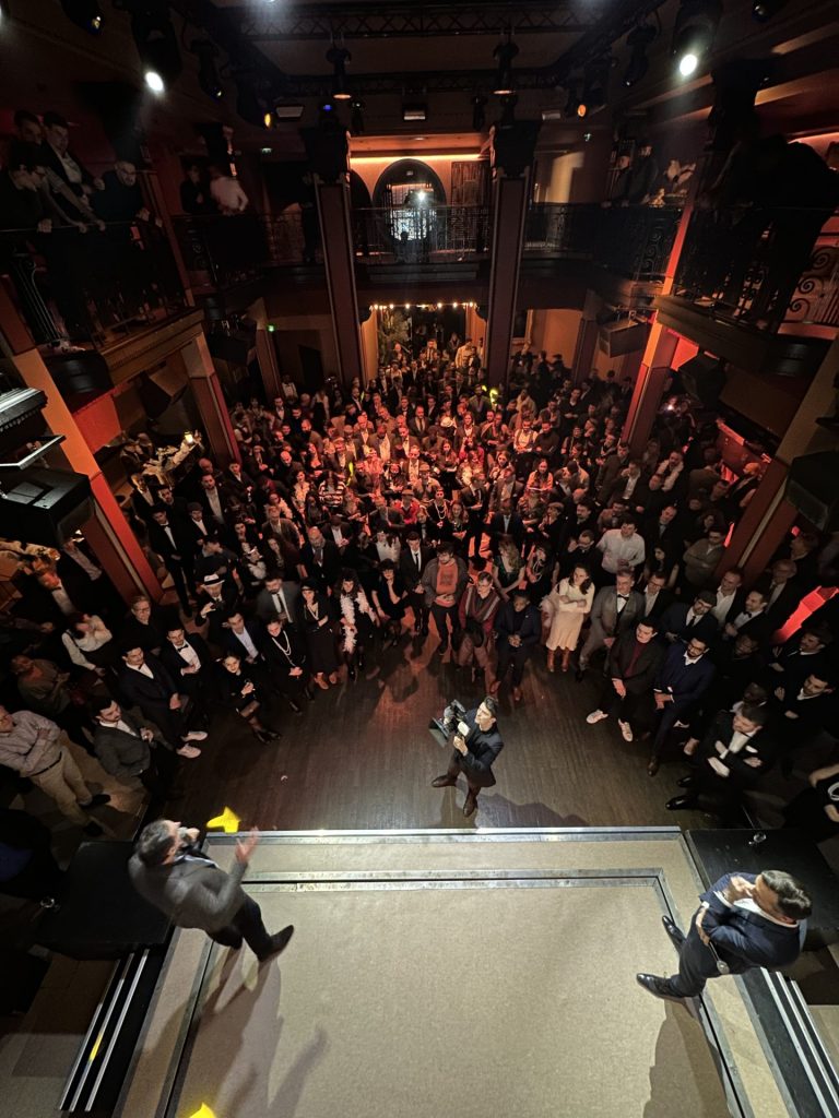 Invités en tenue années folles réunis devant la scène, vus d’en haut, à la soirée awards Scalian organisée par Weevup