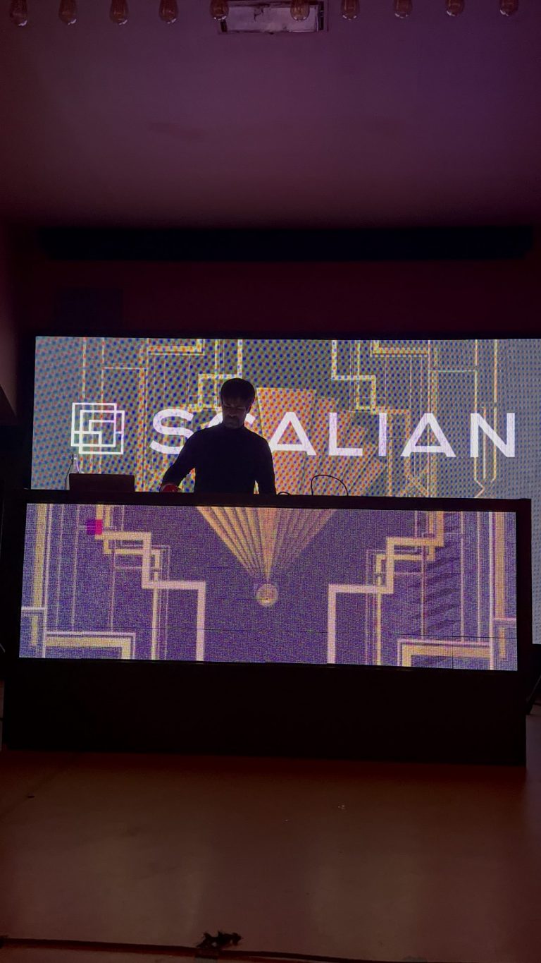 DJ aux platines devant un mur LED aux motifs Art déco et au logo Scalian, pendant la soirée awards années folles