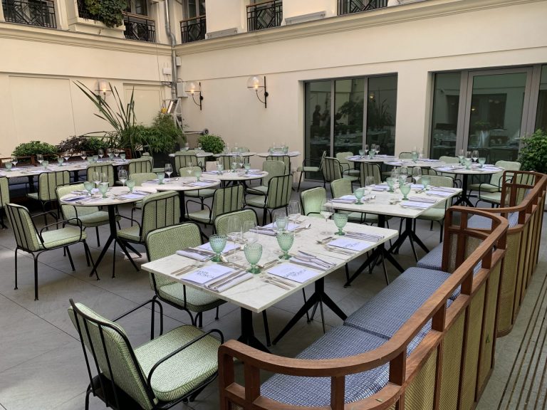 Terrasse de l’hôtel Kimpton avec tables dressées et chaises vertes, prête pour la soirée team building