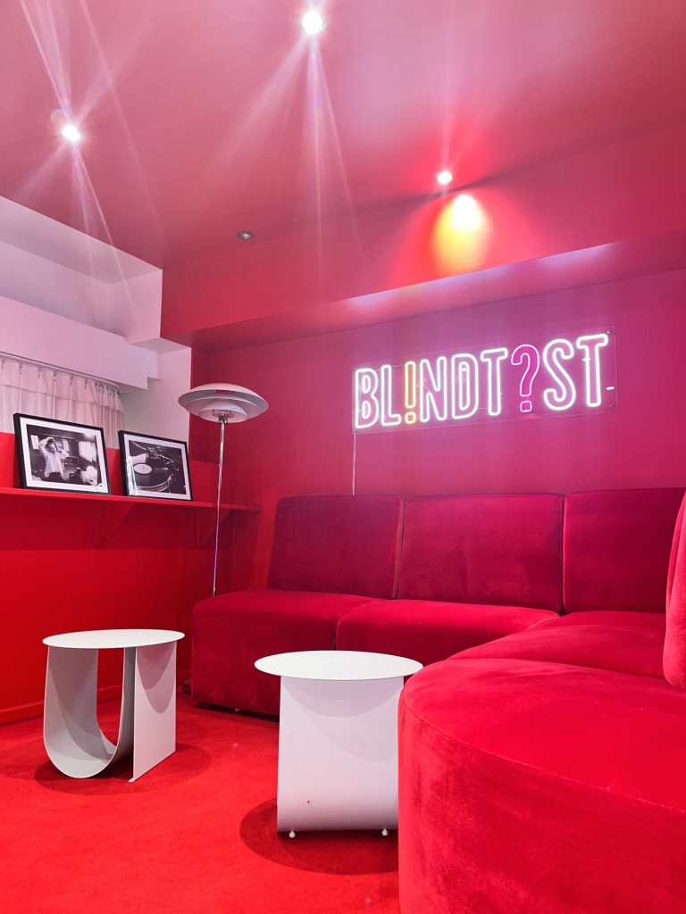 Salle rouge du Studio Nellcote, à Paris, avec banquettes et enseigne lumineuse de blind test, préparée pour la soirée d’entreprise de CMG Consulting