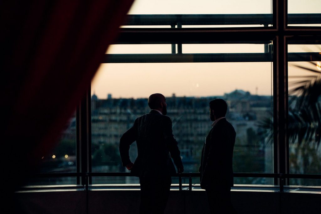 Deux invités en silhouette devant une baie vitrée au coucher du soleil, soirée Interface à l’Institut du monde arabe