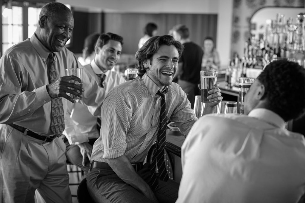 photo en noir et blanc de 3 hommes assis devant un bar, discutant et tenant un verre à l’afterwork ouicar
