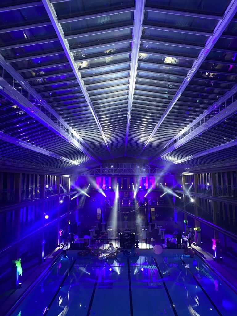 Jeux de lumière sous la verrière et portique d’éclairage au fond de la salle, pendant la soirée d’entreprise fluo de Havea Group organisée par Weevup