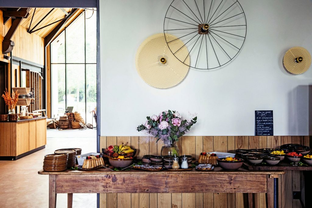 Buffet dressé sur une table en bois avec un bouquet de fleurs, dans le lieu choisi par Weevup pour le séminaire résidentiel du CODIR de Dior