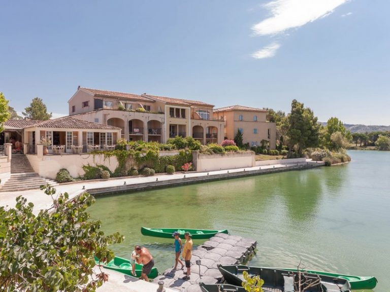 Canoës amarrés à un ponton sur le lac de Pont Royal en Provence, devant les terrasses du village