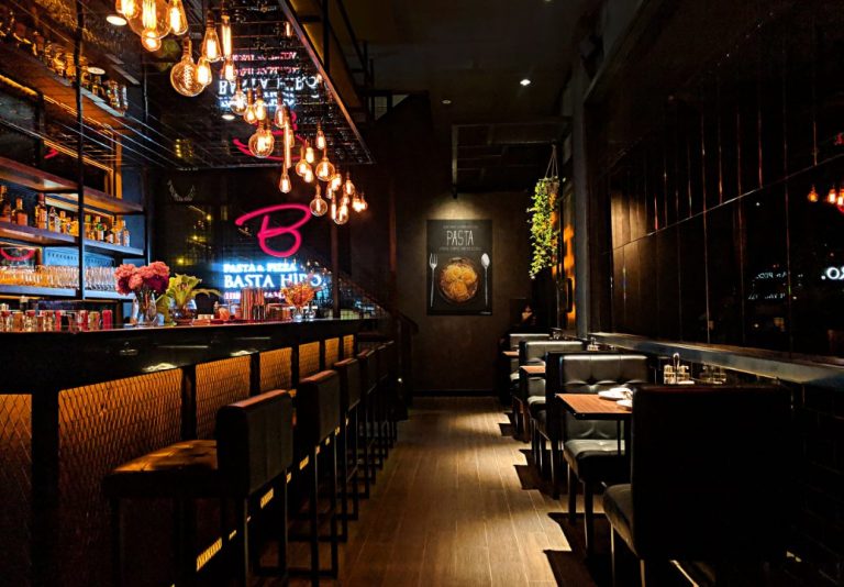 Bar à l’éclairage tamisé avec comptoir, tabourets et banquettes, cadre chaleureux pour un afterwork