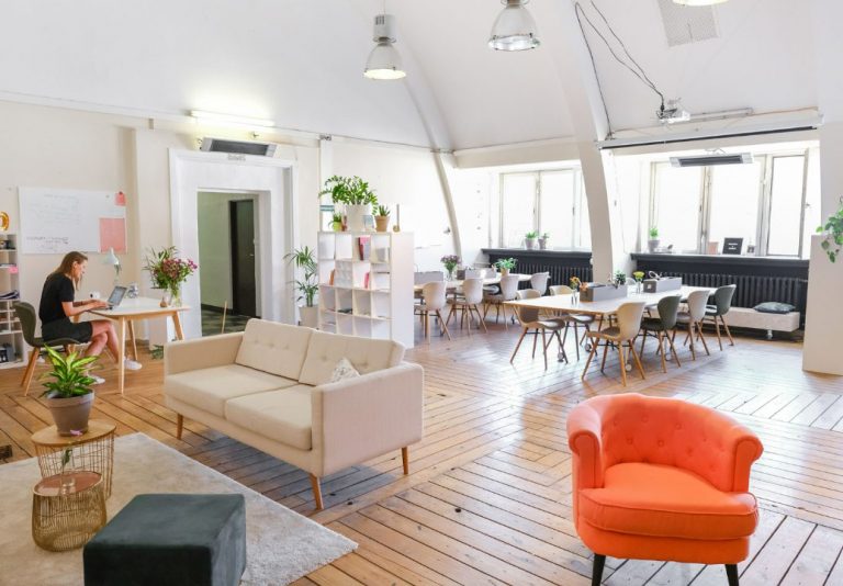 Espace de coworking lumineux avec canapé, fauteuil orange et tables de travail pour une journée d’étude
