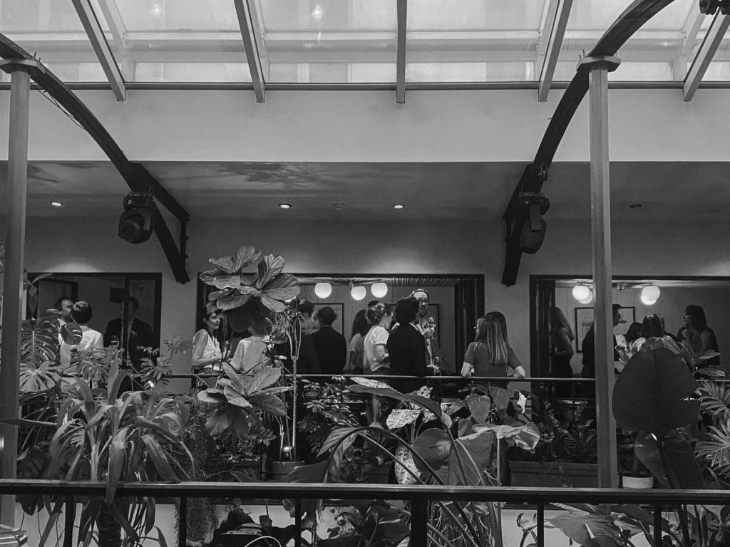 Invités réunis dans le salon de l’Alcazar, vus à travers les plantes de la verrière, pendant le cocktail dînatoire de SVZ organisé par Weevup