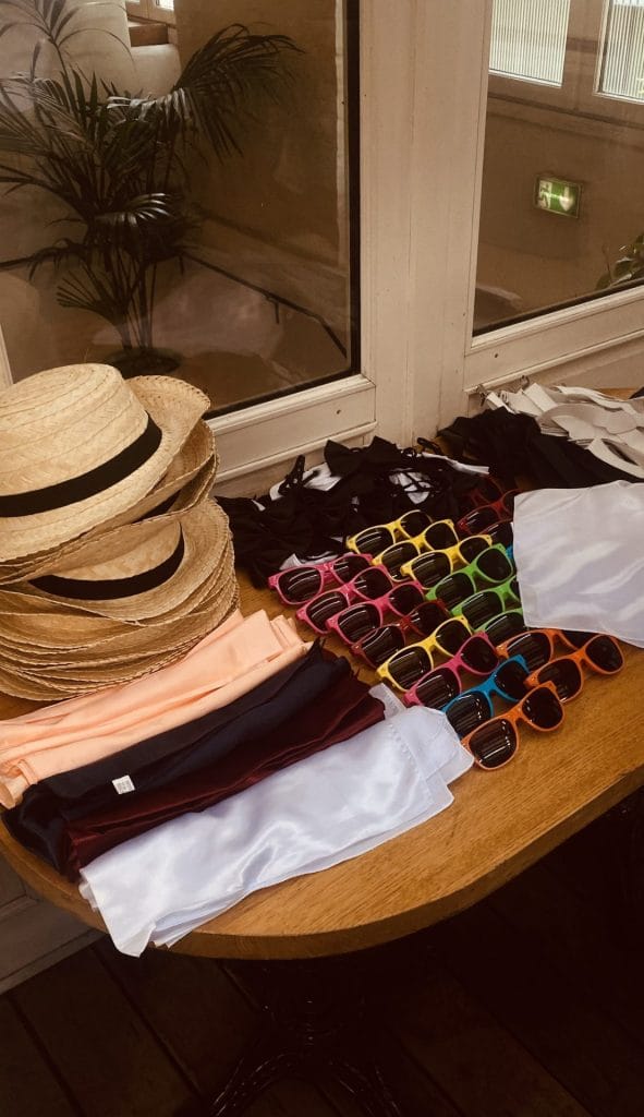 Canotiers en paille, nœuds papillon, foulards et lunettes de soleil colorées disposés sur une table pendant la soirée de rentrée Coty organisée par Weevup