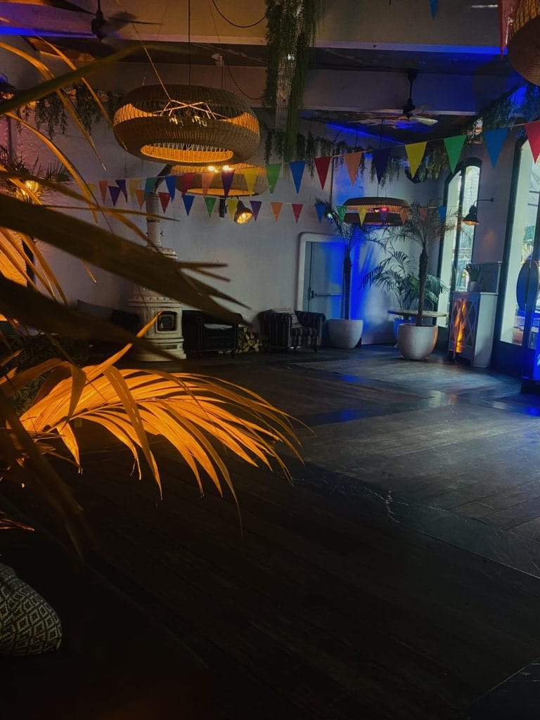 Salle intérieure de la Brasserie d’Auteuil décorée de fanions colorés et de suspensions en osier, sous un éclairage bleu, pour la soirée de rentrée Coty organisée par Weevup