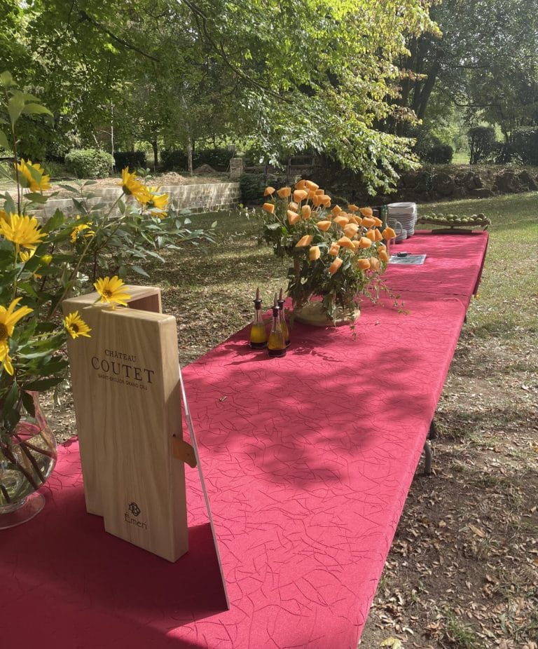 Table nappée de rouge, fleurs jaunes et plaque en bois du Château Coutet, dressée en plein air pour le séminaire de l’Université de Bordeaux
