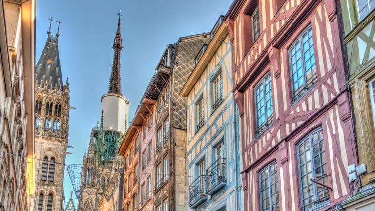 Maisons à colombages colorées d’une rue de Rouen, dominées par la flèche de la cathédrale Notre-Dame