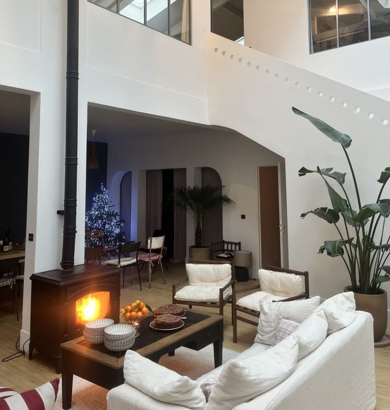 Salon de l’appartement Dune Paris, à Pigalle, avec cheminée allumée et canapés blancs, privatisé pour Insight