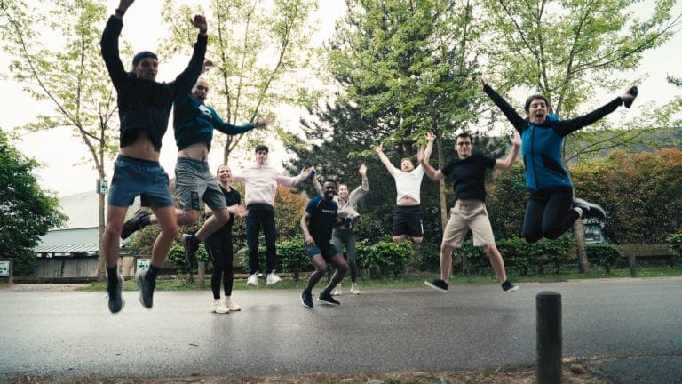 Collaborateurs de KPMG sautant en l’air sur une allée bordée d’arbres, pendant le team building de leur séminaire à Center Parcs