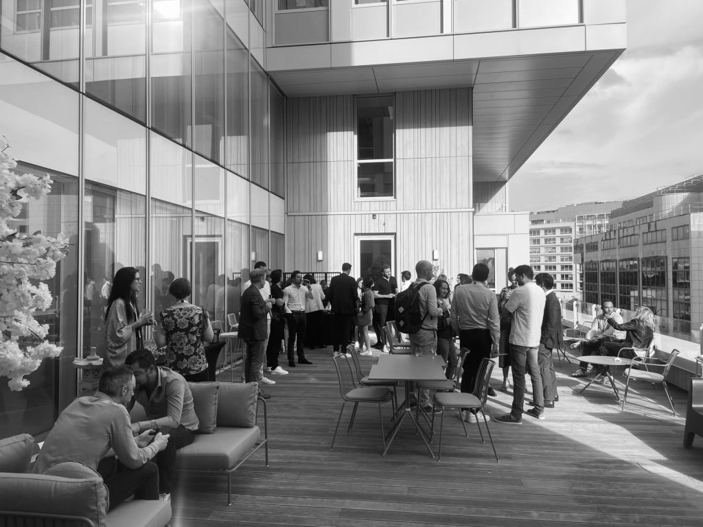 Collaborateurs de Daiichi réunis sur la terrasse en bois de leurs nouveaux bureaux, entre canapés et tables, pendant l’inauguration organisée par Weevup (photo en noir et blanc)