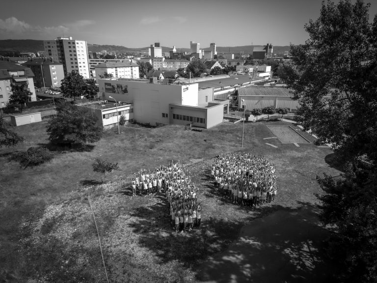 Vue aérienne en noir et blanc des collaborateurs d’Elanco rassemblés sur une pelouse près du site de production de Huningue