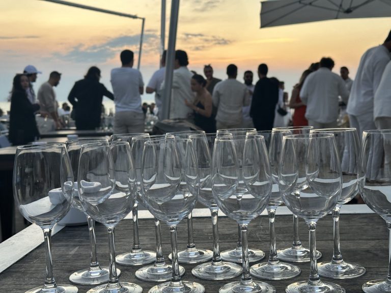 Collaborateurs de MYM réunis au coucher du soleil derrière une rangée de verres, pendant leur séminaire à Biarritz