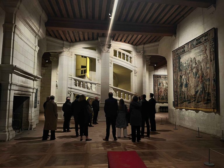 Dirigeants de Generali en visite dans une salle du château de Chambord, entre une grande tapisserie et l’escalier central, pendant leur séminaire annuel