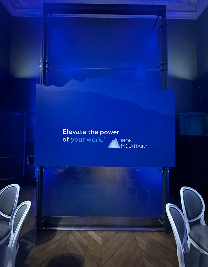 Écran bleu aux couleurs d’Iron Mountain installé pour le dîner au Louvre, élément de la mise en scène créée par Weevup