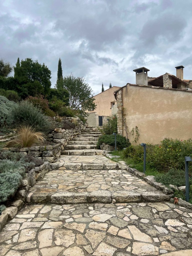 Escalier de pierre bordé de végétation provençale menant aux bâtisses du domaine de Ribiera, lieu du séminaire de Pacific en Provence