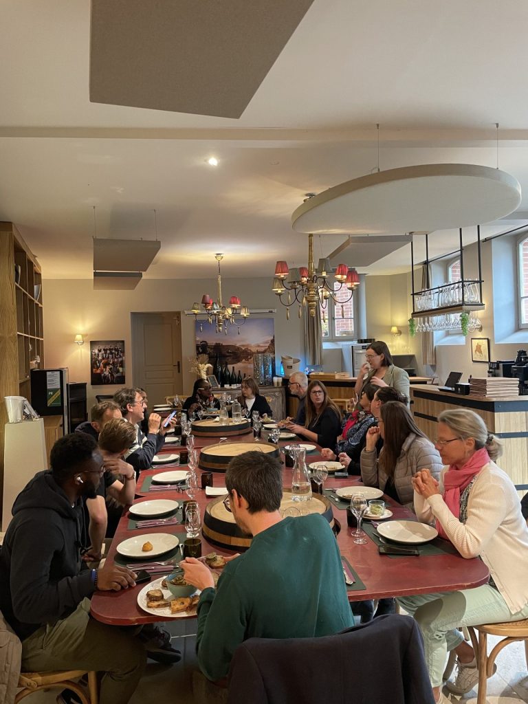 Participants du séminaire de Swiss Life attablés autour d’une longue table, dans une salle de restaurant aux lustres colorés, pendant leurs deux jours à Reims