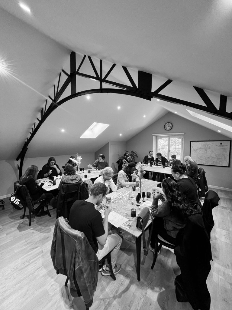 Participants du séminaire Swiss Life attablés dans une salle sous charpente, pendant leur séminaire à Reims, en noir et blanc