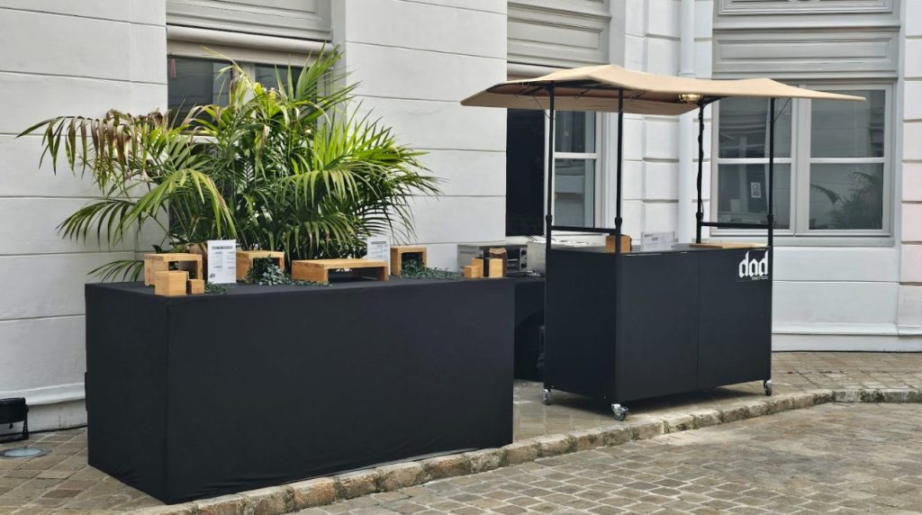 Stands noirs en bois du traiteur avec décorations végétales et présentoirs lors de la Summer Party Coty