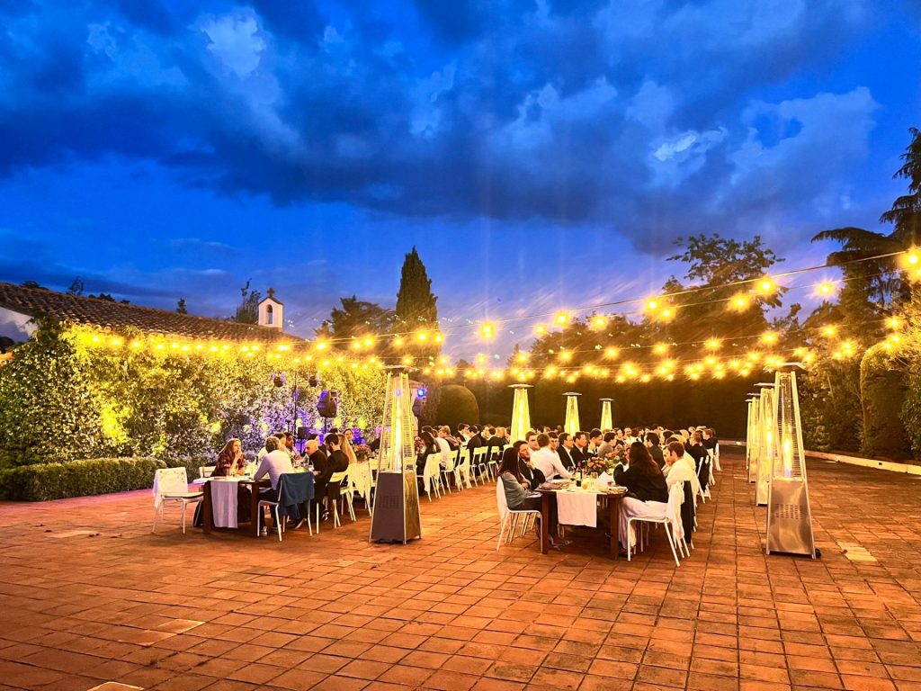 Dîner en terrasse à la tombée de la nuit, tables dressées sous des guirlandes lumineuses, pendant le séminaire Cherry Ventures près de Barcelone