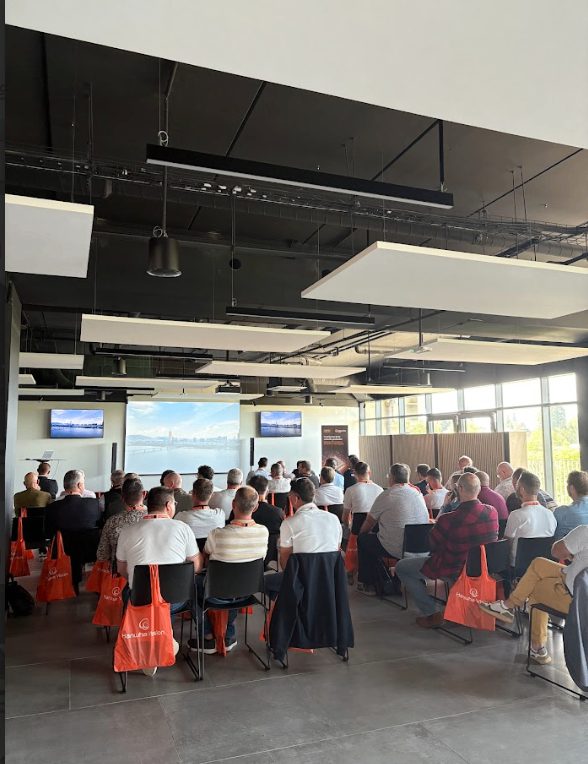 Participants attentifs à une présentation du roadshow Hanwha à Agen, sacs orange Hanwha Vision posés sur les chaises