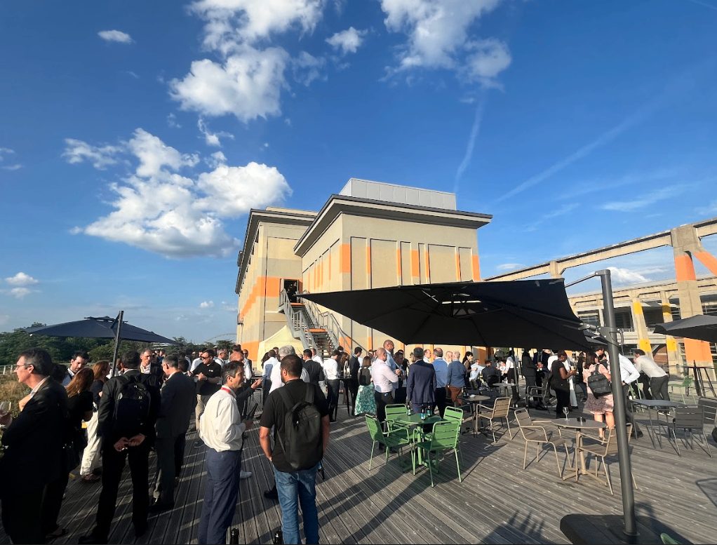 Participants de SBS Connect Paris en pleine discussion sur une terrasse en bois, près d’un parasol et de chaises vertes, événement accompagné par Weevup