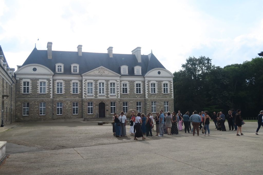 Invités de la soirée annuelle IGAM rassemblés dans la cour d’une demeure en pierre bordée d’arbres, soirée accompagnée par Weevup