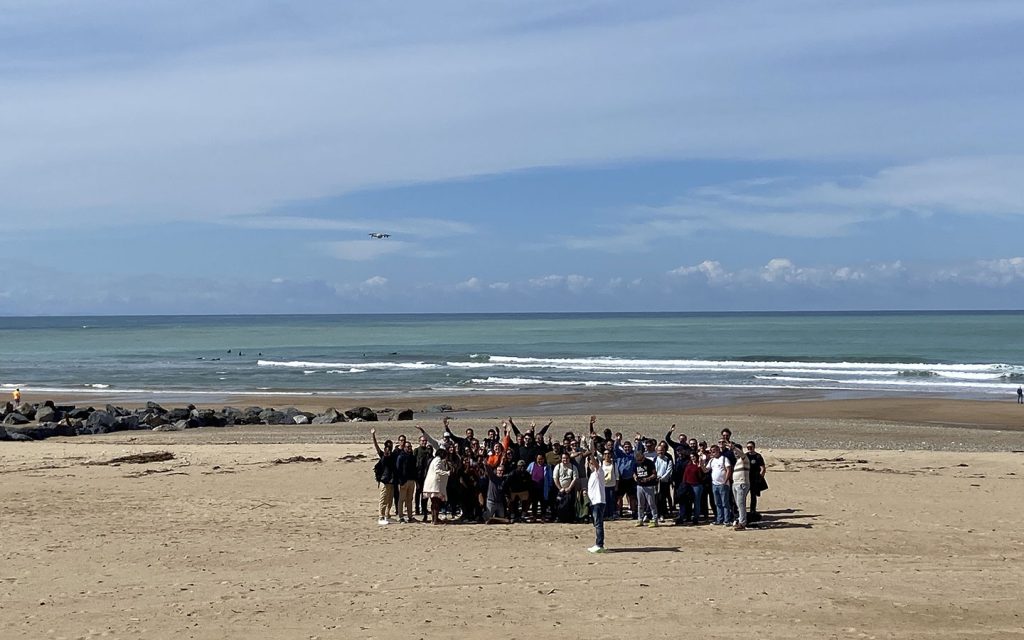 Le groupe du séminaire incentive Libon réuni bras levés sur une plage du Pays basque, séjour organisé par Weevup