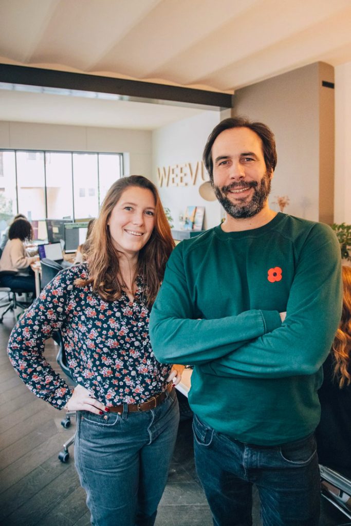 Deux des fondateurs de Weevup dans les bureaux de l’agence, devant le logo Weevup