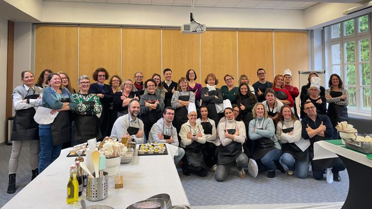 L’équipe R&D de Bio-Rad réunie en tablier pour une photo de groupe dans ses locaux, devant les plats du challenge culinaire
