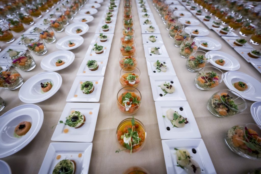 Assiettes et verrines garnies dressées en longues rangées pour la restauration de la convention du Groupe Positive à Bruxelles, organisée par Weevup