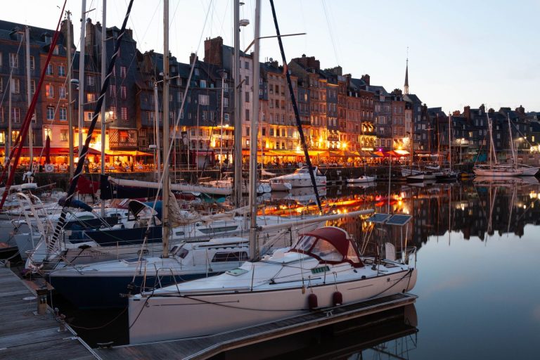 Voiliers amarrés dans le Vieux Bassin de Honfleur à la tombée du jour, devant les hautes maisons du port