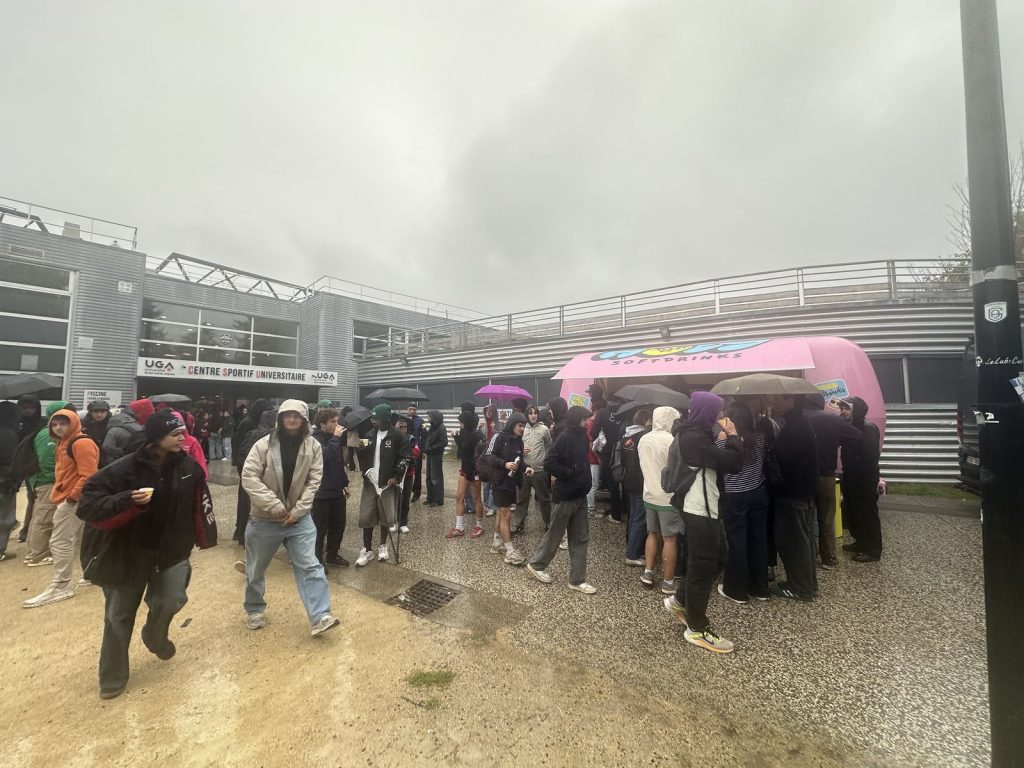 Foule sous la pluie devant la remorque-bar Holy, près d’un centre sportif universitaire, à Grenoble