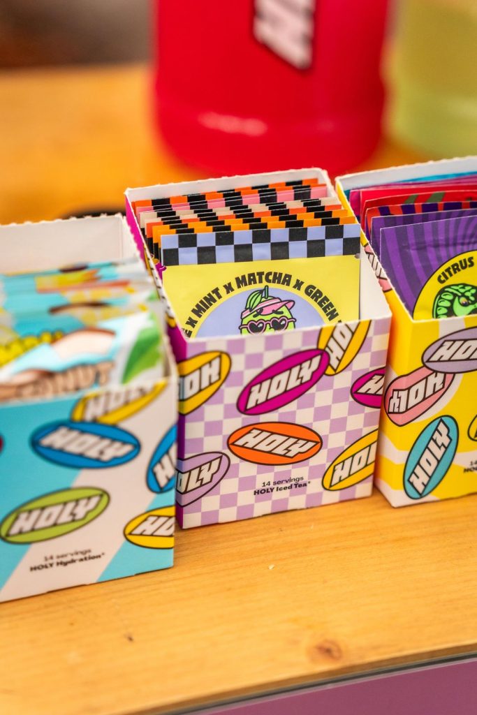 Boîtes de sachets Holy Hydration et Holy Iced Tea ouvertes sur un comptoir en bois